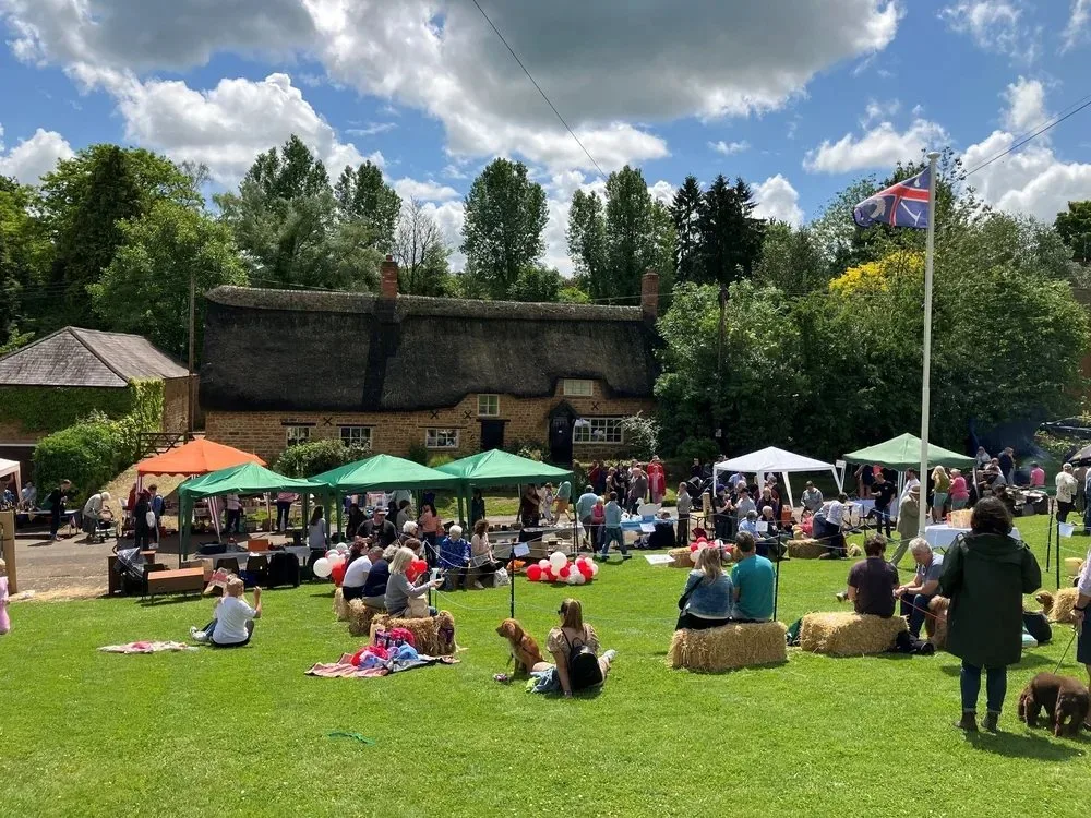 The village fête on the green at Wroxton, beside a thatched cottage